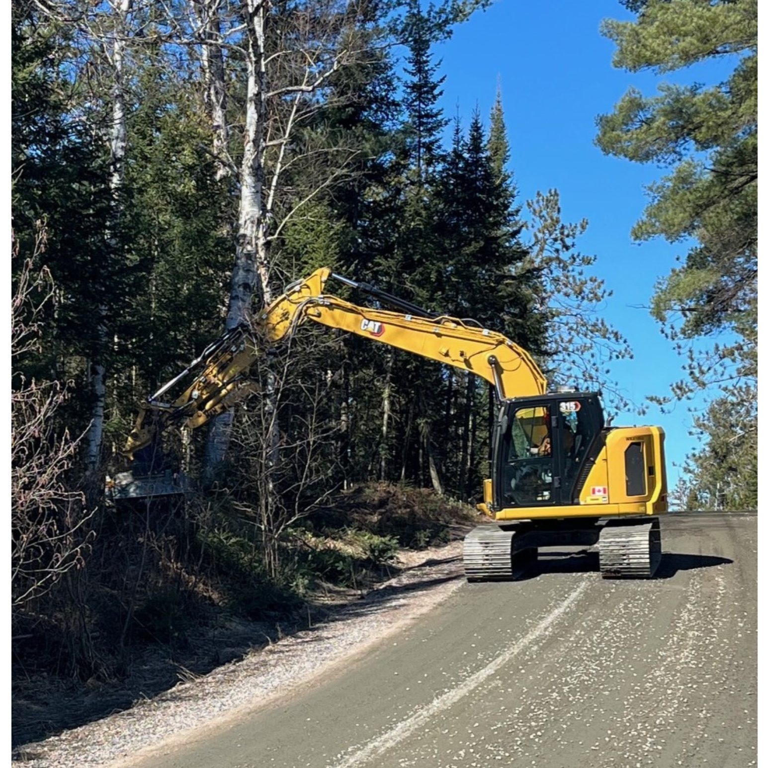 Equipment being used to clear brush on the side of the road.